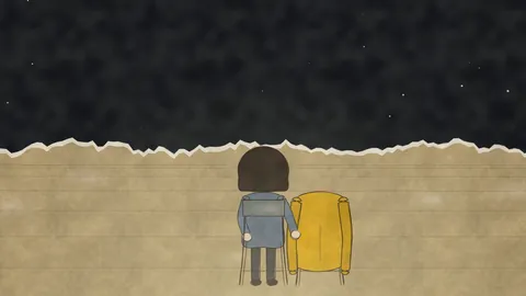 From behind, she sits beside a chair with a yellow raincoat over its back.